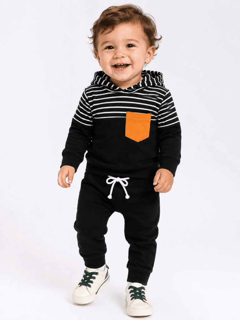 Happy toddler posing in a black kids tracksuit with a striped hoodie and matching joggers.